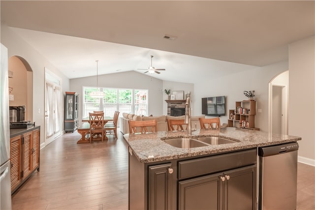 kitchen with light stone countertops, dishwasher, wood-type flooring, lofted ceiling, and sink