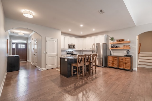 kitchen featuring a breakfast bar, light hardwood / wood-style floors, an island with sink, white cabinetry, and appliances with stainless steel finishes