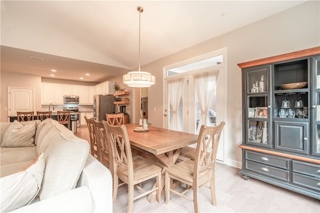 dining area with vaulted ceiling and light hardwood / wood-style floors