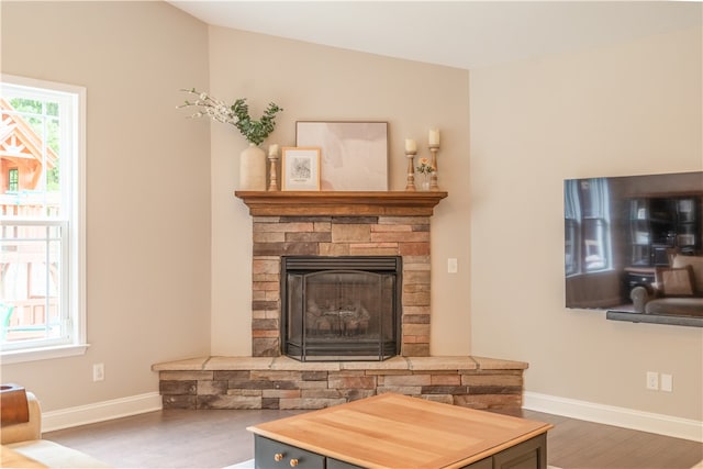 living room with plenty of natural light, hardwood / wood-style floors, and a stone fireplace