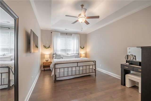 bedroom featuring a tray ceiling, ornamental molding, dark hardwood / wood-style flooring, and ceiling fan