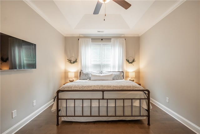 bedroom with ornamental molding, a tray ceiling, dark wood-type flooring, and ceiling fan