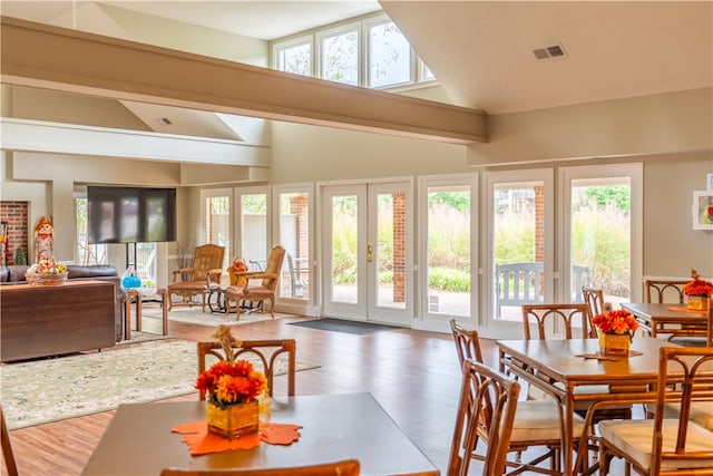 dining room with high vaulted ceiling, dark wood-type flooring, and a healthy amount of sunlight