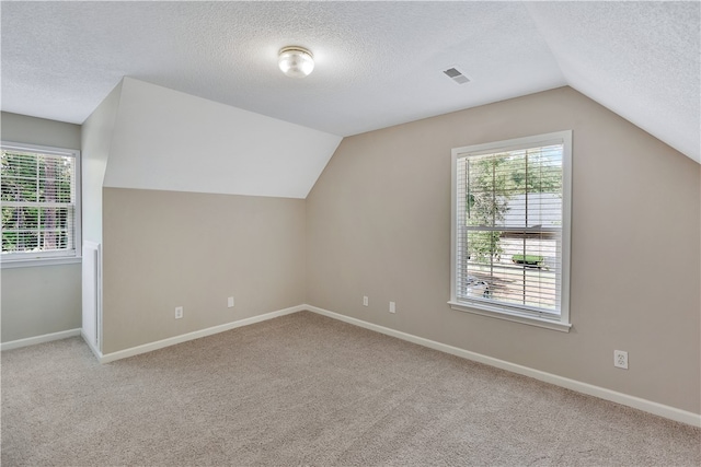 bonus room featuring a textured ceiling, vaulted ceiling, and light carpet