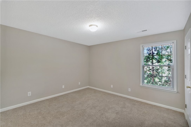 spare room featuring light carpet and a textured ceiling