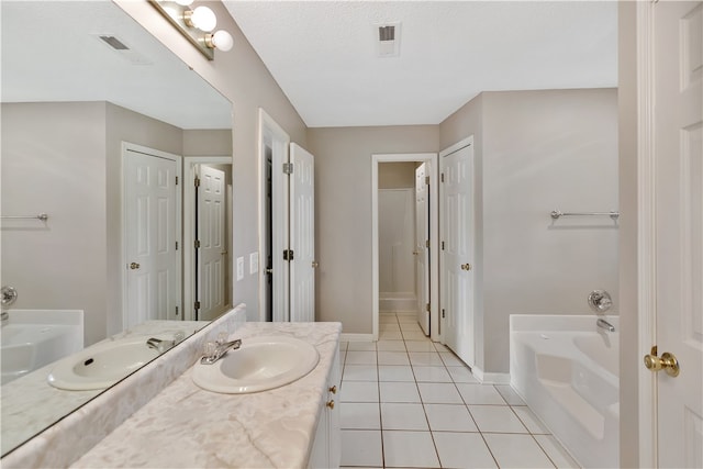 bathroom with tile patterned flooring, a textured ceiling, vanity, and a bathing tub