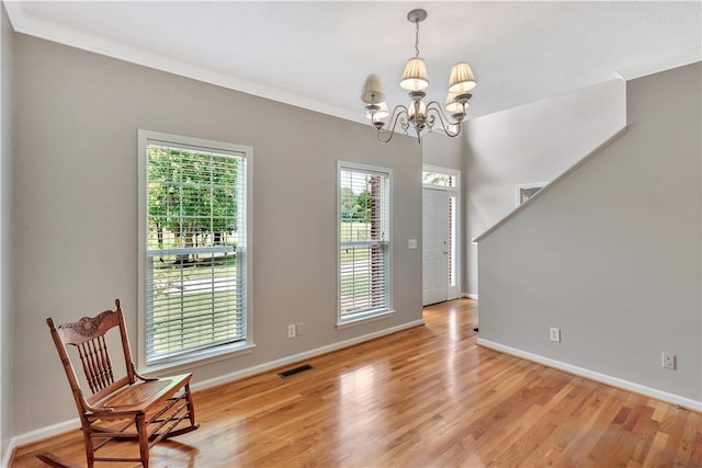 foyer with a notable chandelier, light hardwood / wood-style floors, and ornamental molding