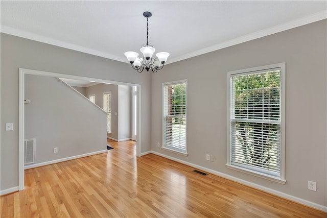 spare room with a notable chandelier, light wood-type flooring, and crown molding