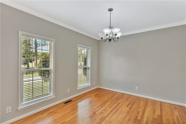 unfurnished room with ornamental molding, an inviting chandelier, and light hardwood / wood-style flooring