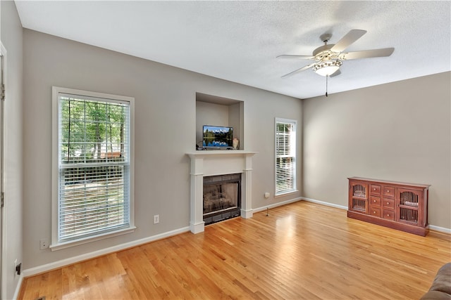 unfurnished living room with hardwood / wood-style flooring, a tile fireplace, plenty of natural light, and ceiling fan