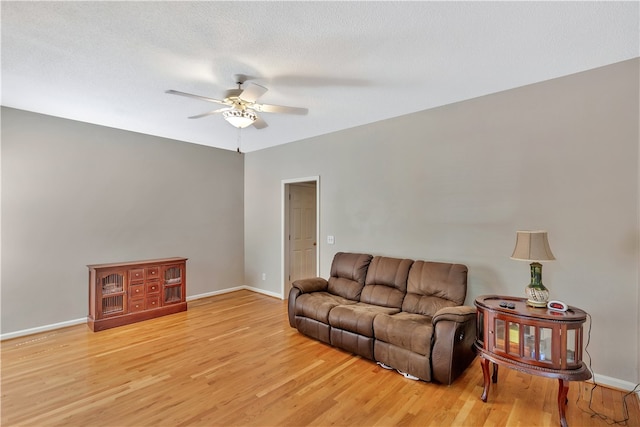 living room featuring a textured ceiling, ceiling fan, and light hardwood / wood-style flooring