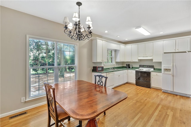 dining space featuring an inviting chandelier, light wood-type flooring, and sink