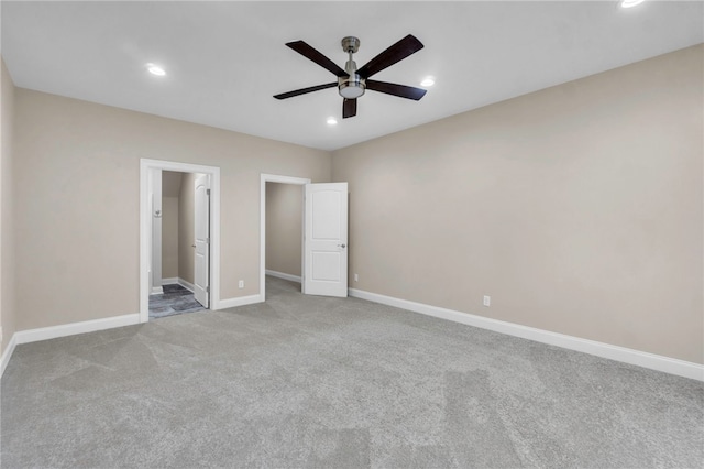 unfurnished bedroom with a spacious closet, ceiling fan, light colored carpet, and ensuite bathroom