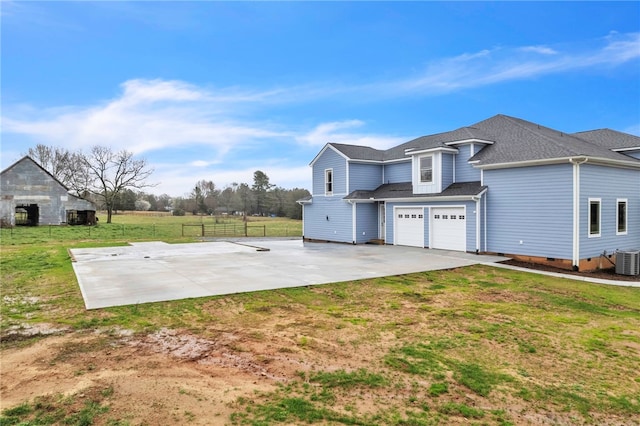 exterior space featuring a patio, a garage, central AC unit, and a front yard