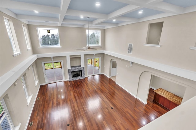 unfurnished living room featuring ceiling fan, beam ceiling, a high end fireplace, dark wood-type flooring, and coffered ceiling