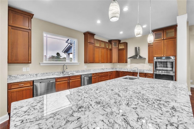 kitchen featuring pendant lighting, stainless steel appliances, sink, and wall chimney range hood