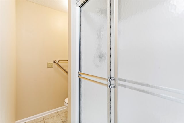 bathroom with tile patterned flooring, a shower with door, and toilet