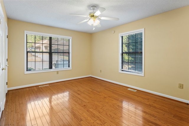 spare room with ceiling fan, plenty of natural light, and wood-type flooring