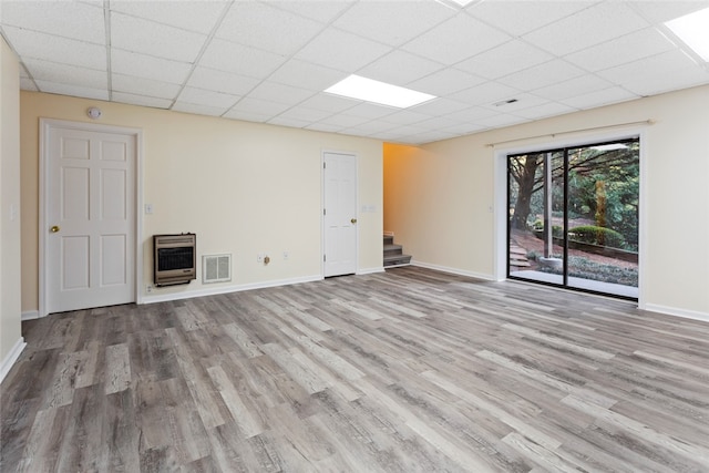 spare room with a drop ceiling, heating unit, and light hardwood / wood-style flooring