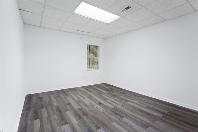 spare room featuring a drop ceiling and dark wood-type flooring