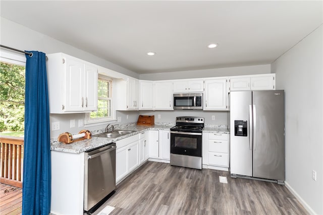 kitchen featuring stainless steel appliances, white cabinetry, plenty of natural light, and sink