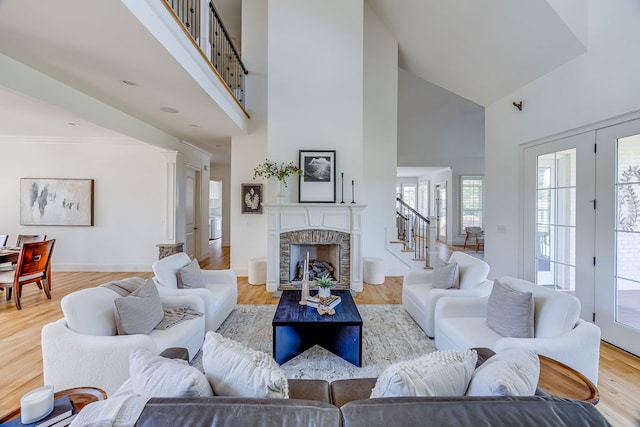 living room with light hardwood / wood-style floors, a fireplace, french doors, and high vaulted ceiling