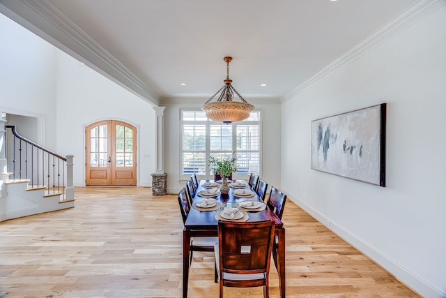 dining room featuring french doors, light wood-type flooring, crown molding, and ornate columns