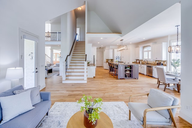 living room with sink, light hardwood / wood-style flooring, and high vaulted ceiling