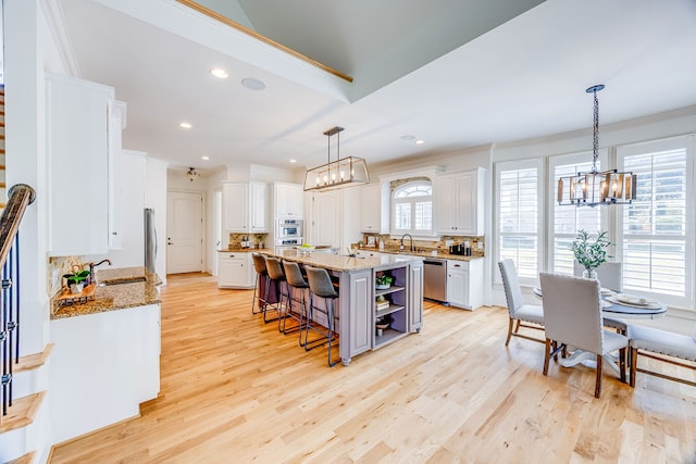 kitchen with a kitchen island with sink, white cabinetry, tasteful backsplash, and a healthy amount of sunlight