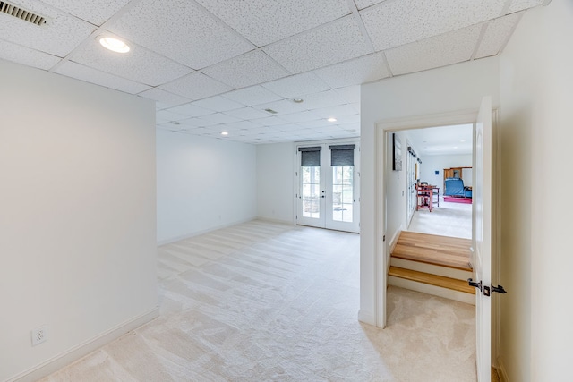 unfurnished room with light colored carpet, french doors, and a paneled ceiling