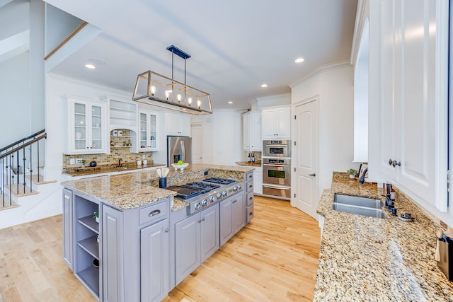 kitchen with decorative light fixtures, a center island with sink, white cabinetry, light hardwood / wood-style floors, and decorative backsplash