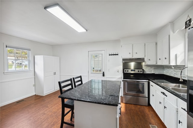 kitchen with stainless steel electric range, white cabinets, backsplash, a kitchen island, and dark hardwood / wood-style flooring