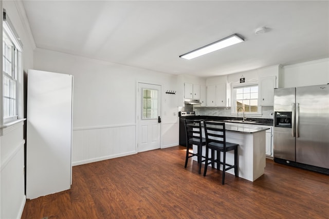 kitchen featuring white cabinets, a breakfast bar, a kitchen island, stainless steel appliances, and dark hardwood / wood-style floors