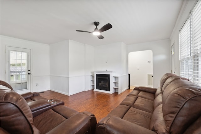 living room featuring ceiling fan, dark wood-type flooring, and crown molding