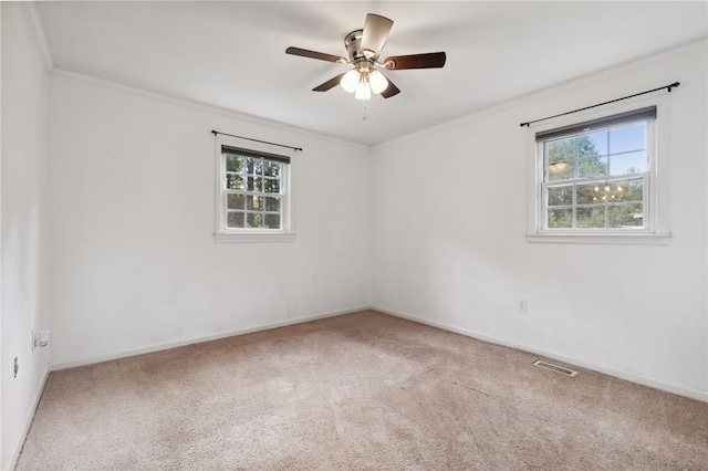 carpeted spare room with ornamental molding, ceiling fan, and a healthy amount of sunlight