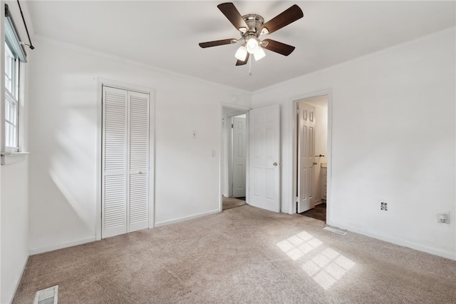 unfurnished bedroom featuring ceiling fan, carpet floors, a closet, and ensuite bath