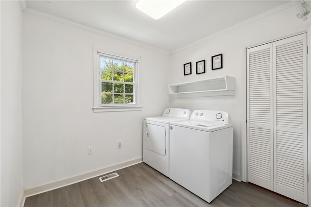 washroom with washing machine and clothes dryer, light hardwood / wood-style flooring, and crown molding