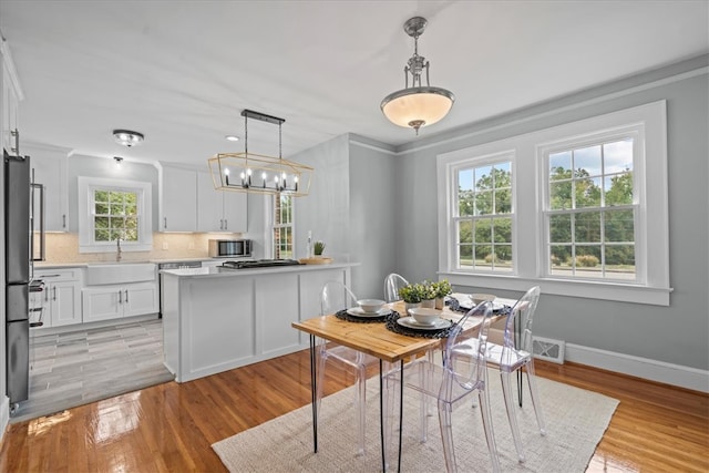 dining room featuring plenty of natural light, crown molding, sink, and light wood-type flooring