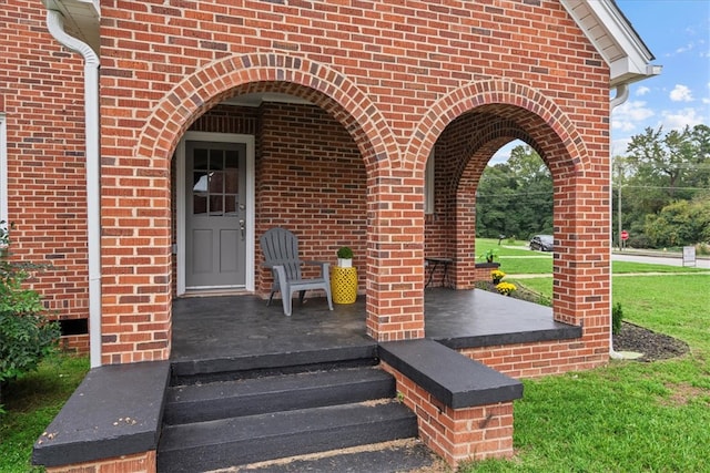 doorway to property with a yard and a porch