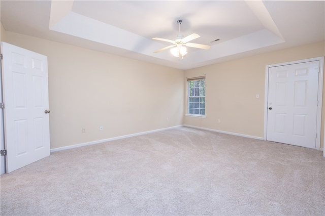 carpeted spare room featuring ceiling fan and a raised ceiling