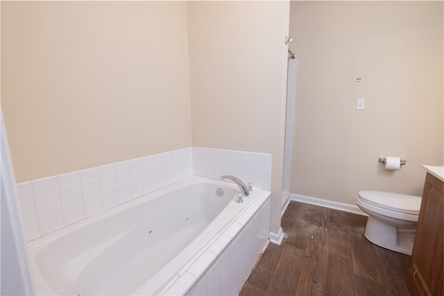 bathroom with vanity, wood-type flooring, toilet, and tiled bath