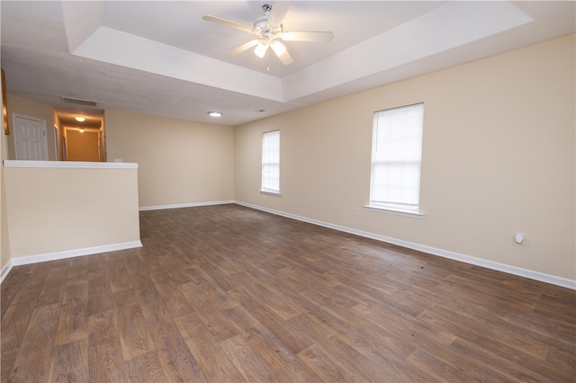 spare room with a tray ceiling, dark wood-type flooring, and ceiling fan