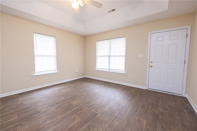 spare room featuring dark wood-type flooring, a tray ceiling, and ceiling fan