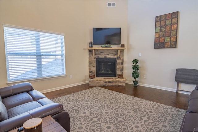 living room with a stone fireplace and dark hardwood / wood-style floors