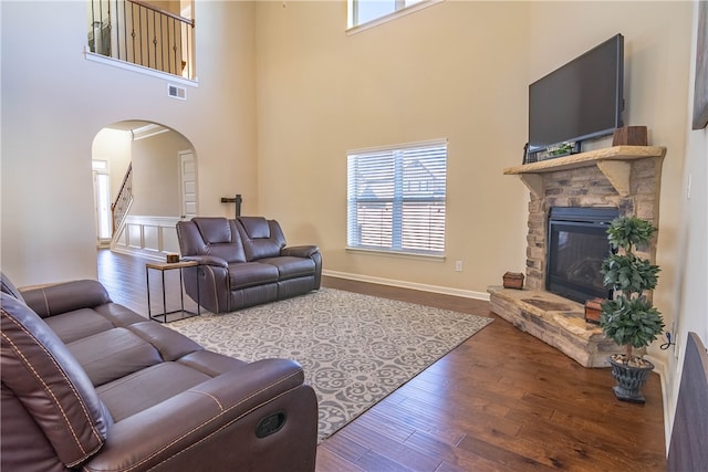 living room featuring a fireplace, a towering ceiling, and hardwood / wood-style flooring