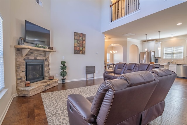 living room with an inviting chandelier, a fireplace, ornamental molding, and dark hardwood / wood-style flooring