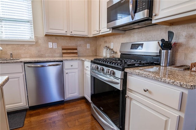 kitchen featuring light stone countertops, stainless steel appliances, dark hardwood / wood-style flooring, and white cabinetry