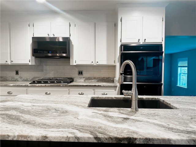 kitchen with sink, white cabinets, decorative backsplash, oven, and gas stovetop