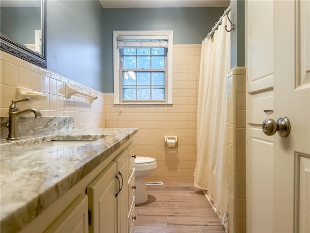 bathroom featuring tile walls, wood-type flooring, vanity, and toilet