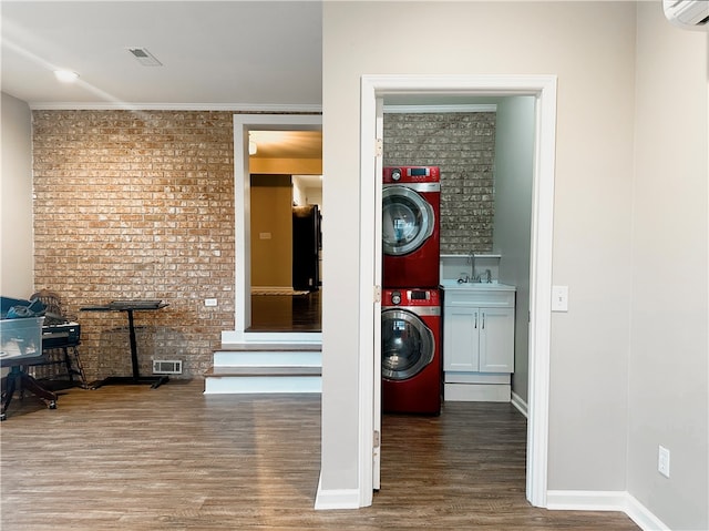 laundry room featuring sink, brick wall, cabinets, hardwood / wood-style flooring, and a wall unit AC